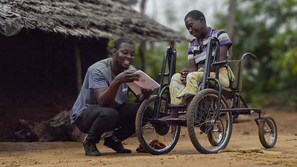 Ken Mwarandu talking to a man on a wheelchair