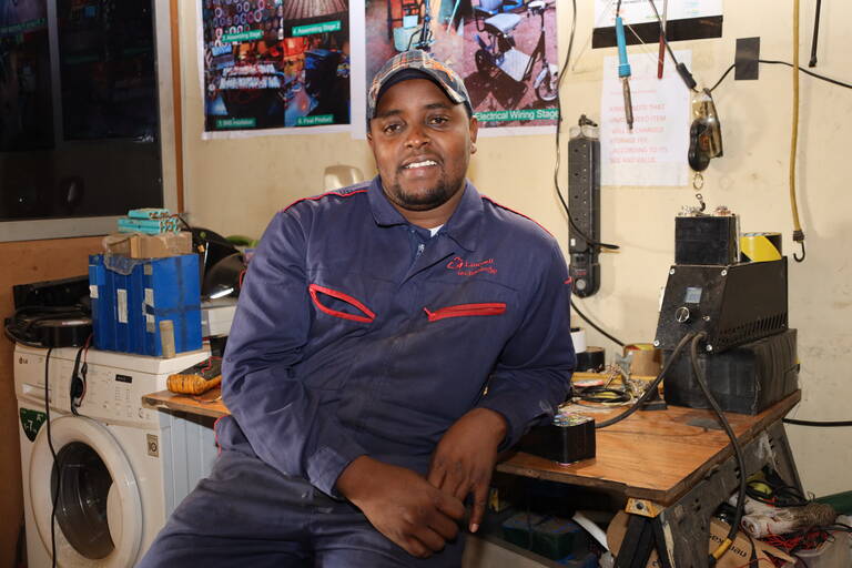 A photo of Lincon seated at his workstation looking into the camera and smiling